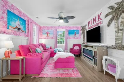a pink living room with a pink couch and a tv at Pink Prerogative Beach Bungalow with Private Pool in Panama City Beach