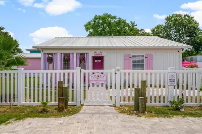 a pink and white house with a white fence at Pink Prerogative Beach Bungalow with Private Pool in Panama City Beach