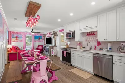 a pink kitchen with a table with pink dishes on it at Pink Prerogative Beach Bungalow with Private Pool in Panama City Beach