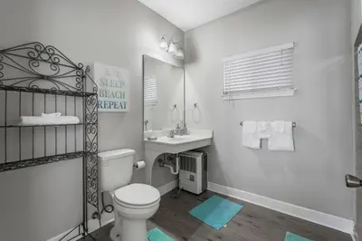a white bathroom with a toilet and a sink at Tranquil Beach & Hot Tub & Pool Getaway in Panama City Beach