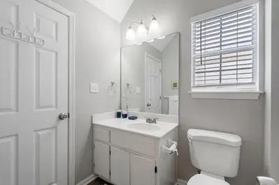 a white bathroom with a toilet and a sink at Tranquil Beach & Hot Tub & Pool Getaway in Panama City Beach