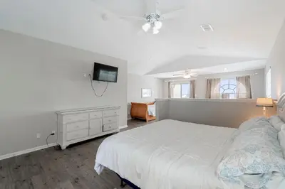a bedroom with a white bed and a television at Tranquil Beach & Hot Tub & Pool Getaway in Panama City Beach