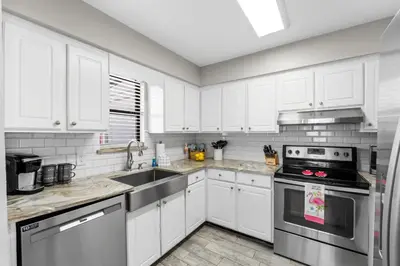 a kitchen with white cabinets and stainless steel appliances at The Pink Flamingo by Book That Condo in Panama City Beach