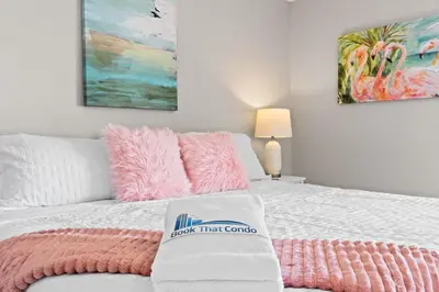 a white bed with a pink blanket on it at The Pink Flamingo by Book That Condo in Panama City Beach