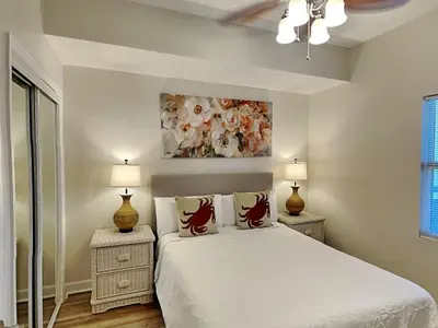 a white bedroom with a bed and two lamps at Seychelles #206 in Panama City Beach