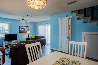 a living room with blue walls and a couch and a table at Horizon Breeze - Family Escape in Panama City Beach