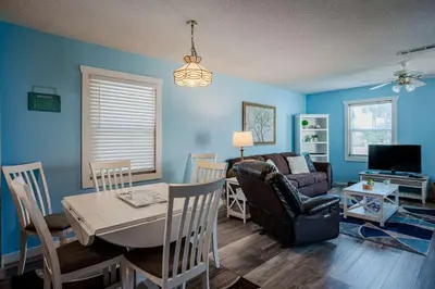 a living room with blue walls and a table and a couch at Horizon Breeze - Family Escape in Panama City Beach
