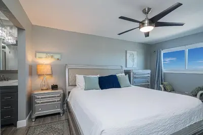 a bedroom with a bed and a ceiling fan at Mariners Retreat - High Rise Beach Living in PCB in Panama City Beach