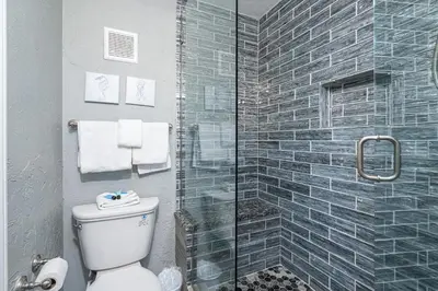 a bathroom with a toilet and a glass shower at Mariners Retreat - High Rise Beach Living in PCB in Panama City Beach