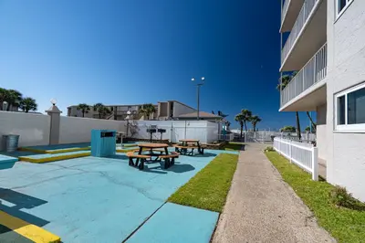 two picnic tables on a sidewalk next to a building at Mariners Retreat - High Rise Beach Living in PCB in Panama City Beach
