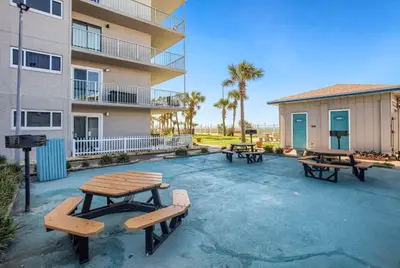three picnic tables in a parking lot in front of a building at Ocean View Retreat - Beachfront Bliss in Panama City Beach