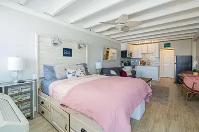 a bedroom with a pink bed and a living room at Coral Cove Beachfront Condo for 3 with Onsite Pool in Panama City Beach