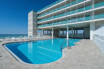 a large swimming pool in front of a building at Coral Cove Beachfront Condo for 3 with Onsite Pool in Panama City Beach