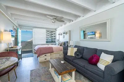 a living room with a couch and a bed at Coral Cove Beachfront Condo for 3 with Onsite Pool in Panama City Beach