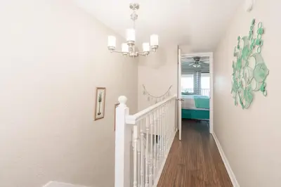 a white staircase in a home with a chandelier at Sea Forever - Cozy Oceanfront Condo in Panama City Beach