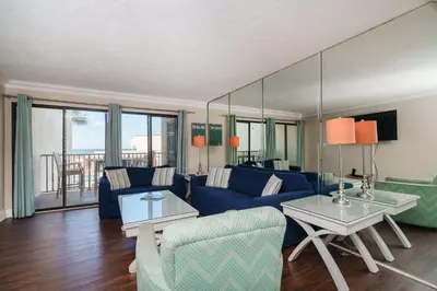 a living room with a blue couch and a table at Sea Forever - Cozy Oceanfront Condo in Panama City Beach