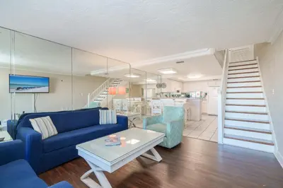 a living room with a blue couch and a table at Sea Forever - Cozy Oceanfront Condo in Panama City Beach