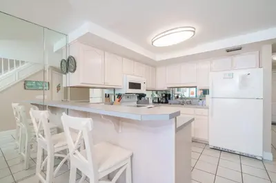 a kitchen with white cabinets and white appliances at Sea Forever - Cozy Oceanfront Condo in Panama City Beach