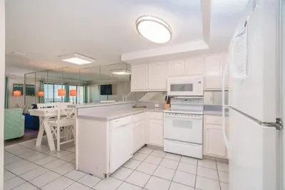 a kitchen with white cabinets and a white refrigerator at Sea Forever - Cozy Oceanfront Condo in Panama City Beach