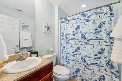 a bathroom with a blue and white shower curtain at Seaside Harmony - Stunning High-Rise Resort Condo in Panama City Beach