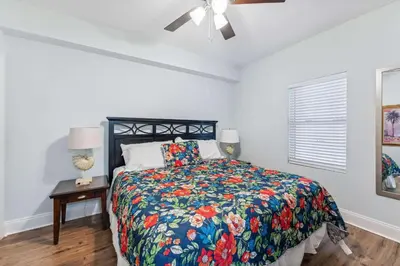 a bedroom with a bed with a floral bedspread and a ceiling fan at Seaside Harmony - Stunning High-Rise Resort Condo in Panama City Beach