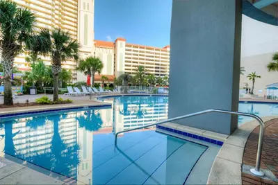 a pool at a hotel with palm trees and a building at Seaside Harmony - Stunning High-Rise Resort Condo in Panama City Beach