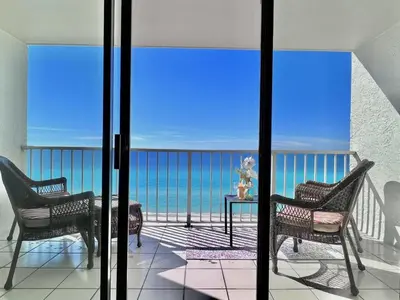 a balcony with two chairs and a table and the ocean at Once Upon A Dream - Beachfront Bliss in Panama City Beach