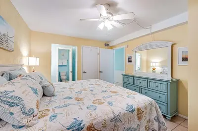 a bedroom with a bed and a dresser and a ceiling fan at Beach Bliss Family Beachfront Living in Panama City Beach