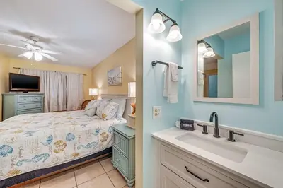 a bedroom with a bed with a sink and a mirror at Beach Bliss Family Beachfront Living in Panama City Beach