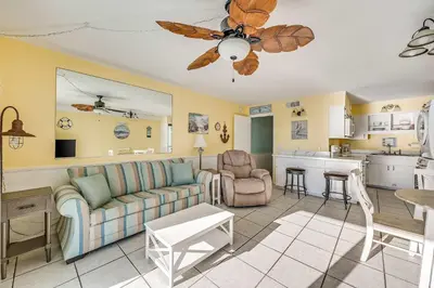 a living room with a couch and a kitchen at Beach Bliss Family Beachfront Living in Panama City Beach