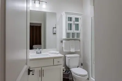 a white bathroom with a toilet and a sink at Sandy Feet Retreat - Ocean View Condo in Panama City Beach