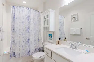 a bathroom with a sink and a toilet and a mirror at Sandy Feet Retreat - Ocean View Condo in Panama City Beach