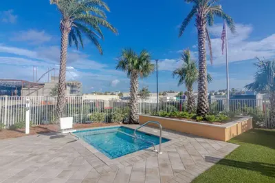 a swimming pool in a yard with palm trees at Sandy Feet Retreat - Ocean View Condo in Panama City Beach