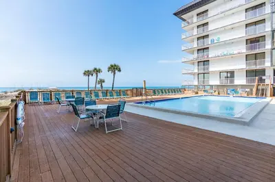 a patio with a table and chairs next to a swimming pool at Beachfront Days Ocean View Condo Bliss in Panama City Beach