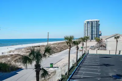 a view of a beach with palm trees and a building at Bethys Beachy Beauty Regency Towers in Panama City Beach