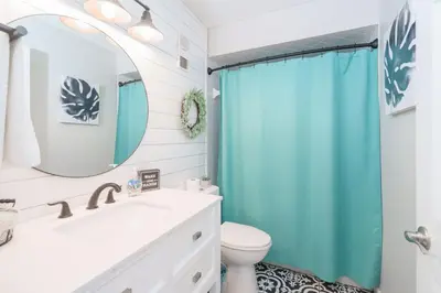 a bathroom with a blue shower curtain and a toilet at Bethys Beachy Beauty Regency Towers in Panama City Beach
