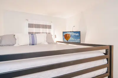 a bedroom with a large bed with white walls at Bethys Beachy Beauty Regency Towers in Panama City Beach