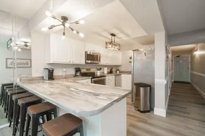 a kitchen with a large counter with stools in it at Bethys Beachy Beauty Regency Towers in Panama City Beach