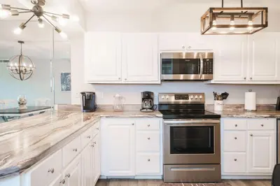 a kitchen with white cabinets and stainless steel appliances at Bethys Beachy Beauty Regency Towers in Panama City Beach