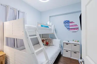 a white bunk bed with a ladder in a room at Sunrise Sands - An Unforgettable Vacation for 7 in Panama City Beach