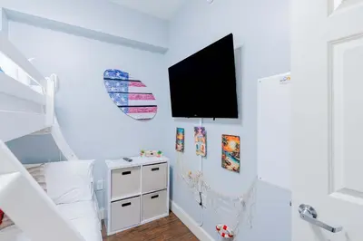 a white room with a bed and a tv on the wall at Sunrise Sands - An Unforgettable Vacation for 7 in Panama City Beach