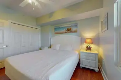 a bedroom with a white bed and a lamp on a night stand at Sunrise Serenity - Resort Condo in Panama City Beach