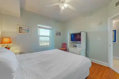 a bedroom with a white bed and a flat screen tv at Sunrise Serenity - Resort Condo in Panama City Beach
