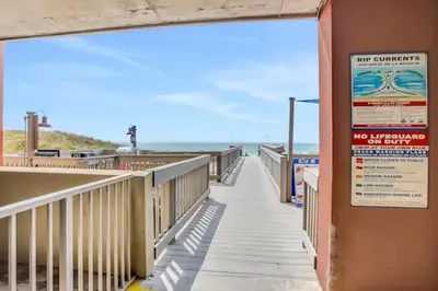 a walkway to the beach with a no entry sign at Sunrise Serenity - Resort Condo in Panama City Beach