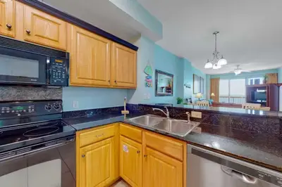 a kitchen with wooden cabinets and a stainless steel sink at Sunrise Serenity - Resort Condo in Panama City Beach