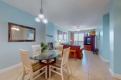 a dining room and living room with a table and chairs at Sunrise Serenity - Resort Condo in Panama City Beach