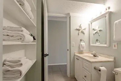 a bathroom with a sink and a mirror and towels at Sunrise Sunset - Full Ocean Views in Panama City Beach
