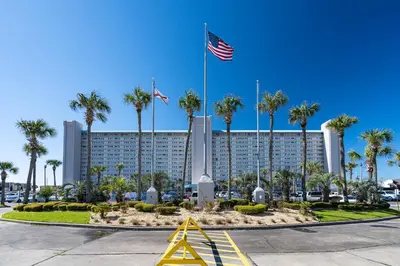 a building with palm trees and an american flag at Sunrise Sunset - Full Ocean Views in Panama City Beach