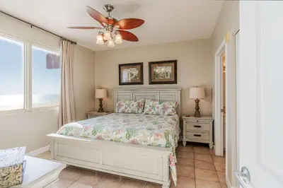 a bedroom with a bed and a ceiling fan at Sunset Shores - Oceanfront Condo Bliss in Panama City Beach