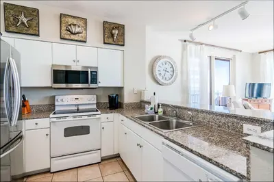 a kitchen with a sink and a stove top oven at Sunset Shores - Oceanfront Condo Bliss in Panama City Beach